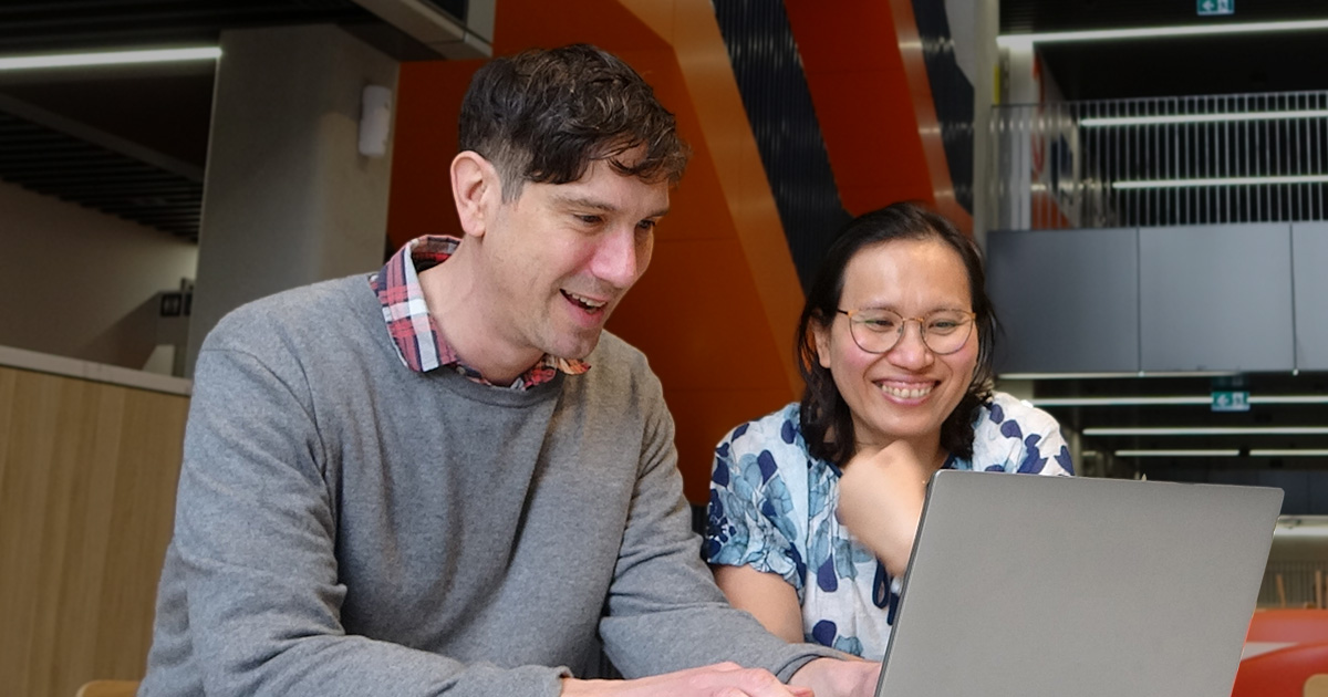 Julian working on his laptop with his co-supervisor Preeyaporn