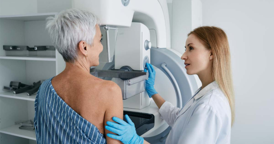 An older woman getting a mammogram with the help of a young radiographer