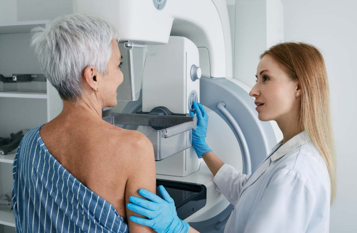 An older woman getting a mammogram with the help of a young radiographer