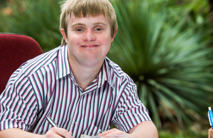 A young person with Down Syndrome filling out a form