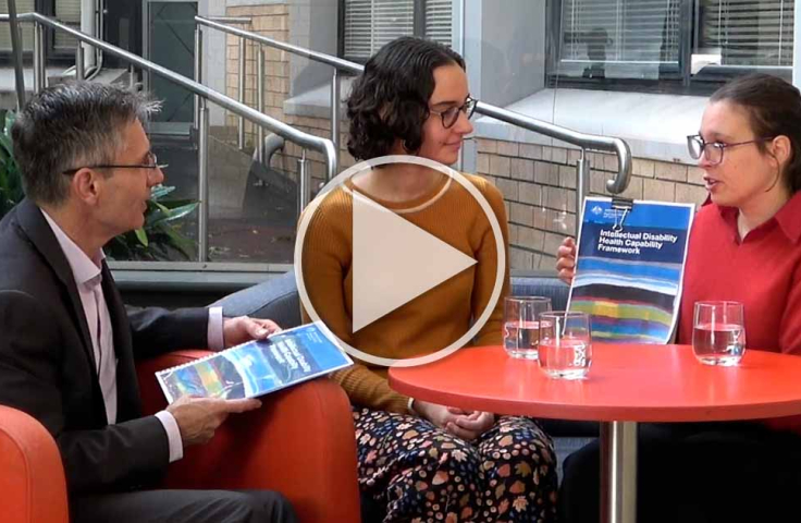 Julian, Emil and Tahli talking in a cafe with printed copies of the framework